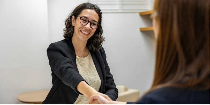 Business analyst candidate shaking hands with an interviewer during a professional interview.