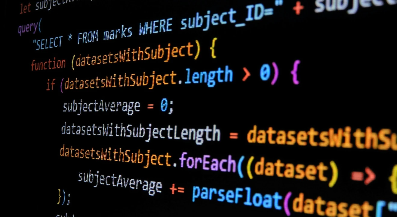 Close-up of colorful programming code displayed on a computer screen, featuring SQL queries, JavaScript functions, and data processing logic.