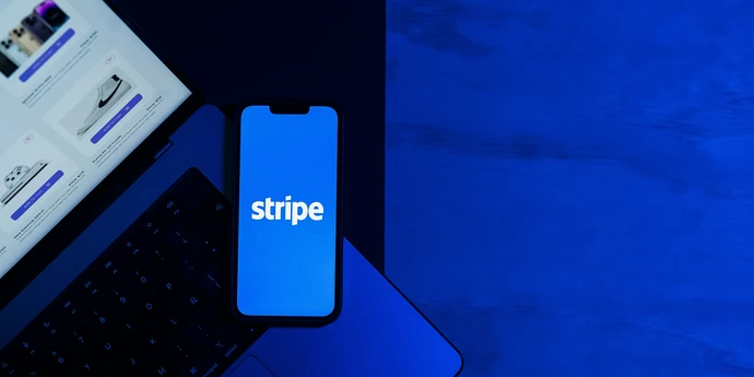 stripe logo showing on a phone placed on a laptop