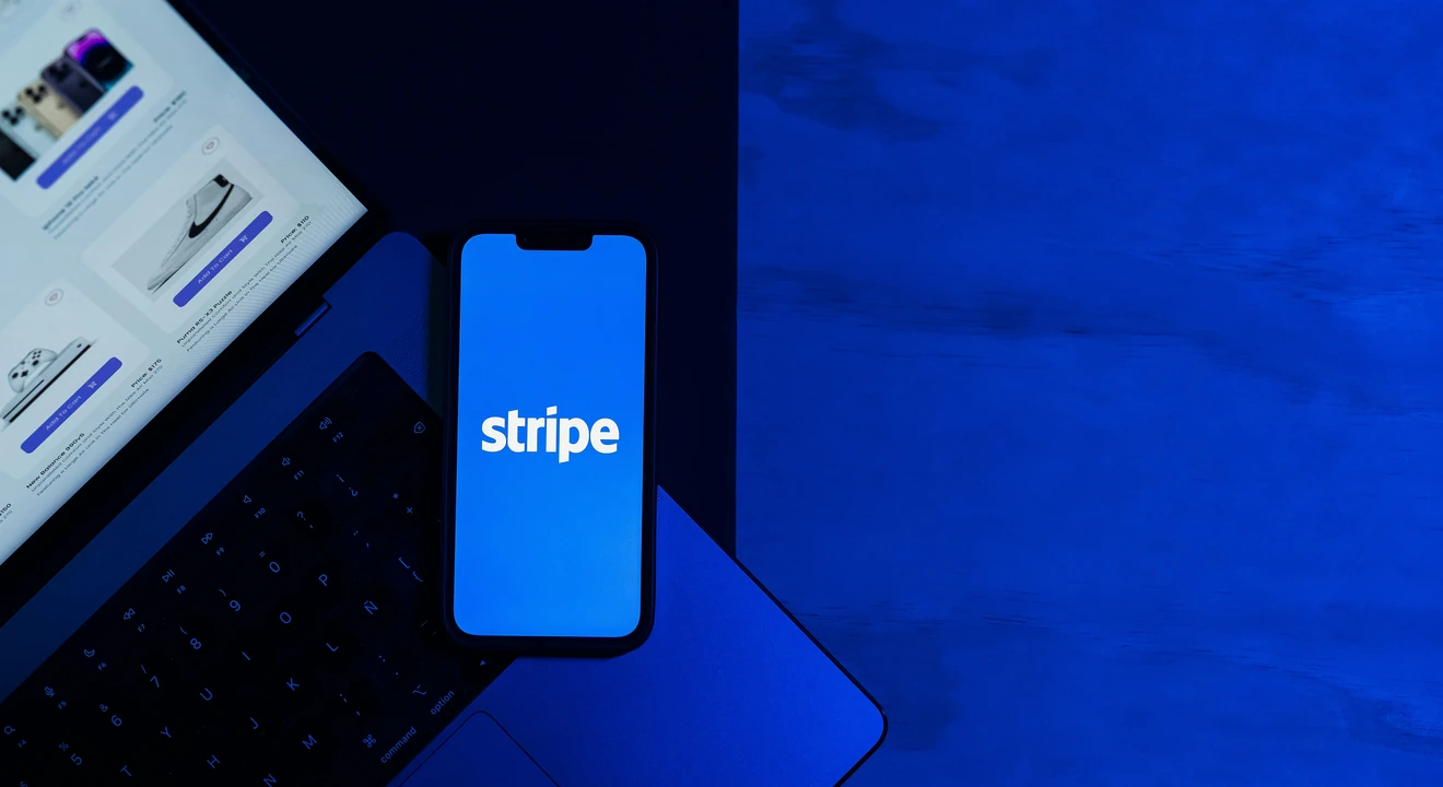 stripe logo showing on a phone placed on a laptop