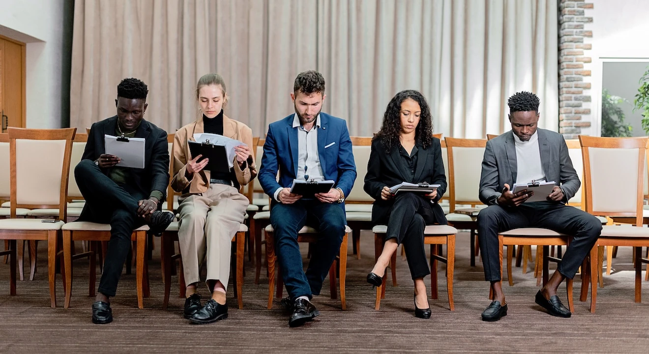 Job candidates waiting for interviews while reviewing their resumes and notes